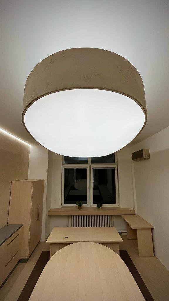 Moderní ložnice s kulatým napnutým stropem v béžové barvě a vestavěným LED osvětlením nad postelí.