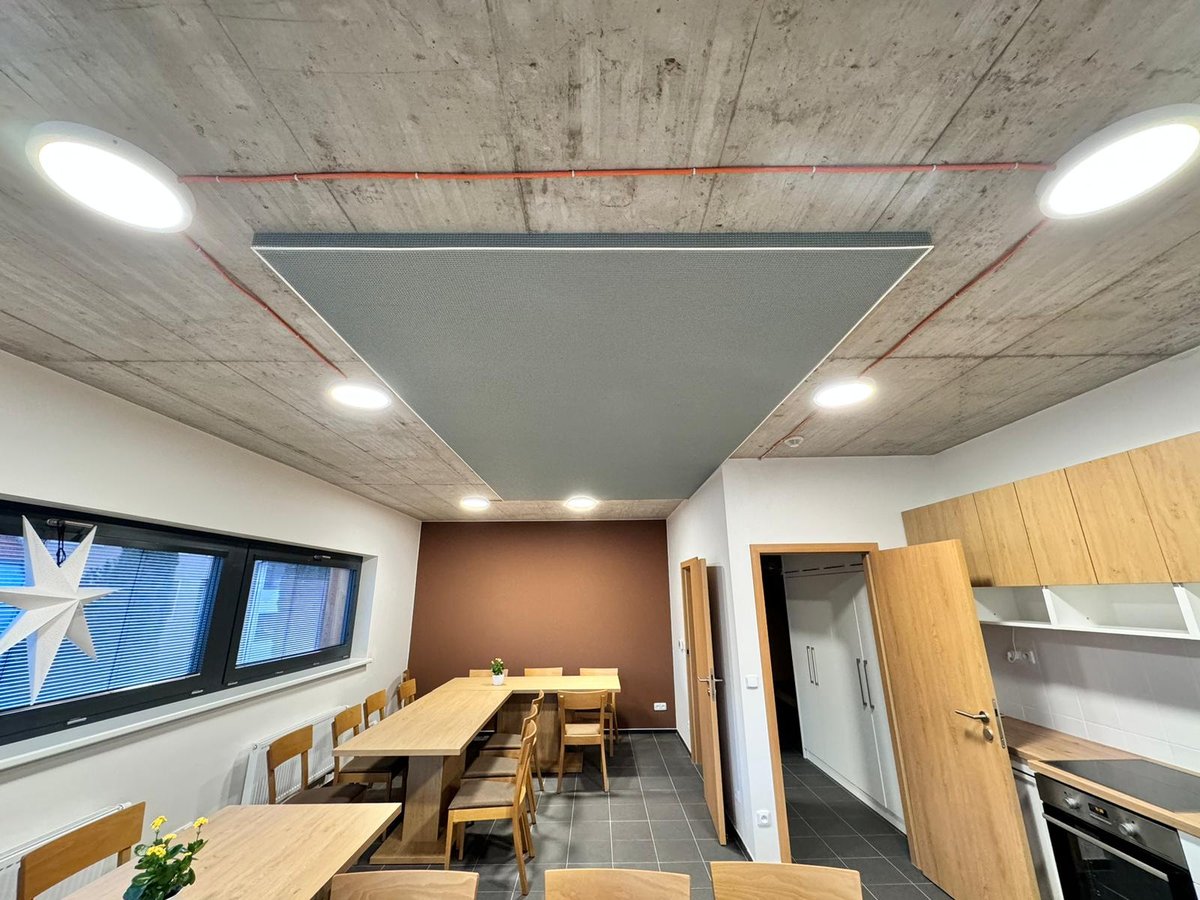 Moderní kancelářský prostor s napínaným stropem v šedé barvě, integrovaným LED osvětlením a akustickým panelem uprostřed stropu.