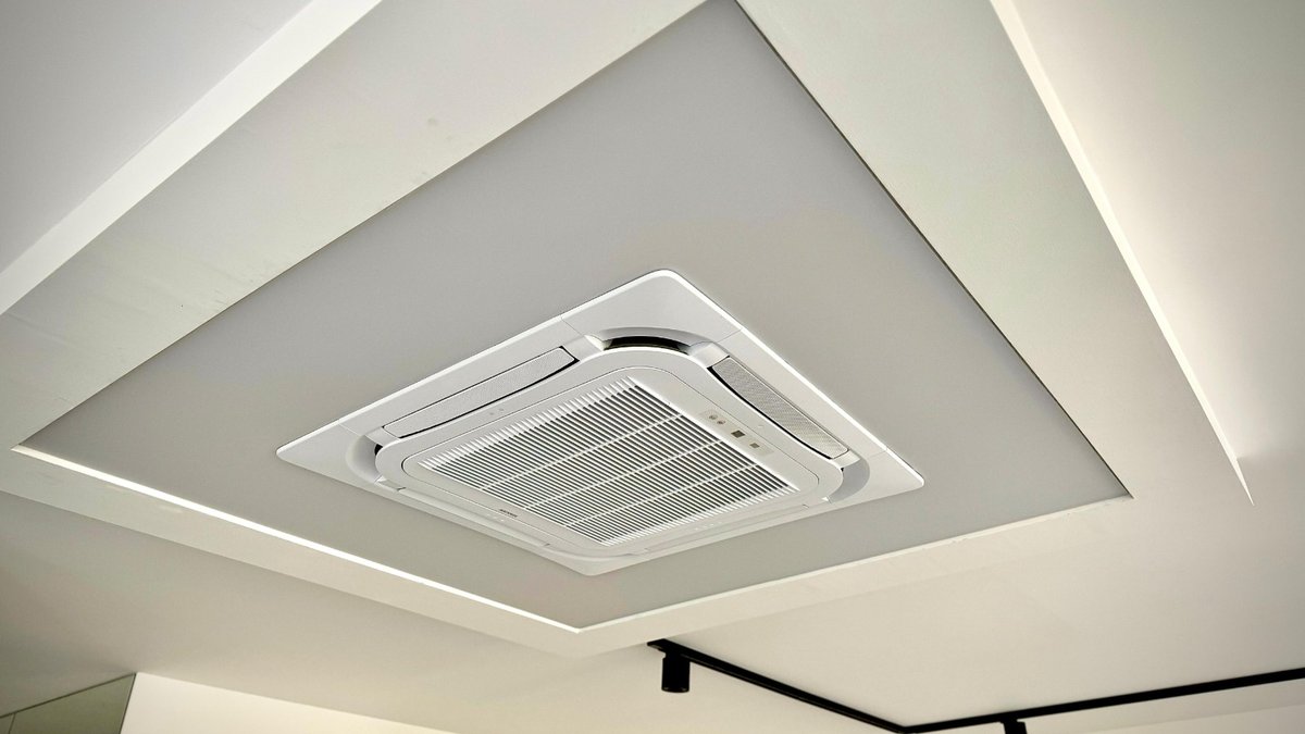 Moderní napínaný strop s vestavěným kasetovým klimatizačním jednotkou a elegantním LED osvětlením v kancelářské místnosti.