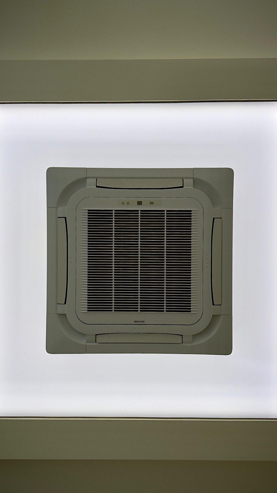 Nainstalovaná kazetová jednotka klimatizace v napínaném stropu s integrovaným designem a bílým napínacím plnem.